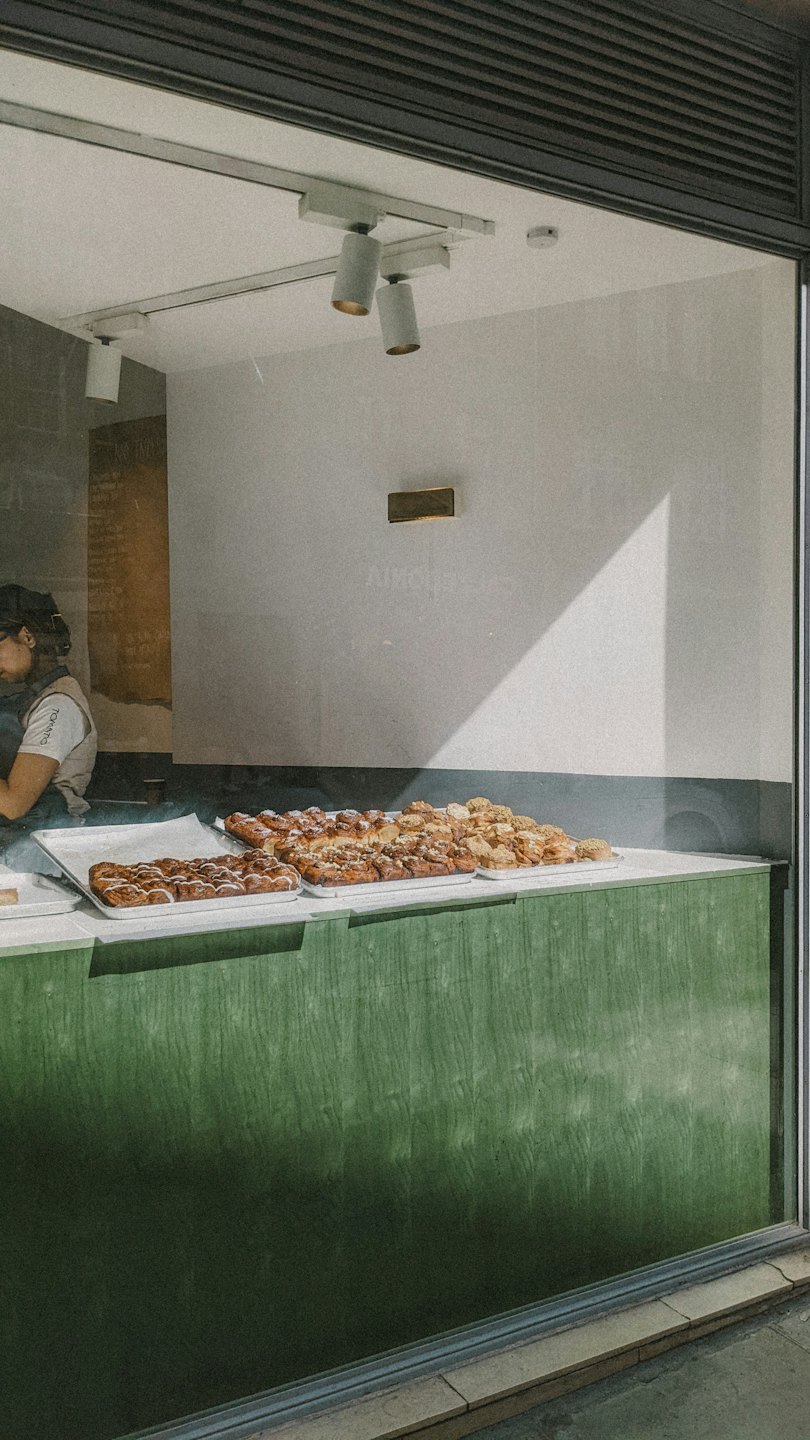 Baked goods and cinnamon rolls displayed on a wooden counter.